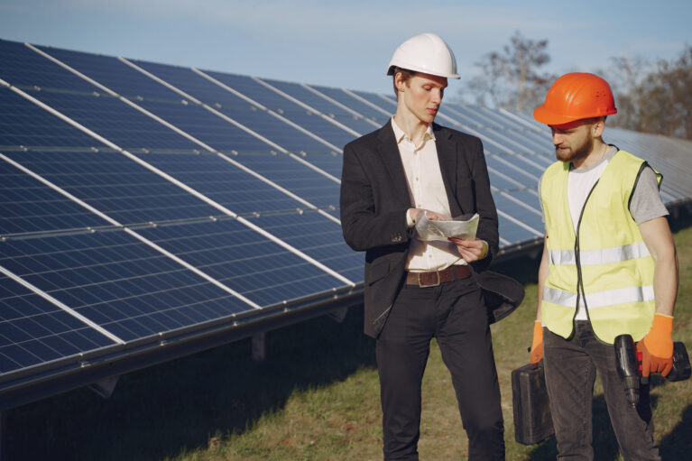 Businessman and worker near solar energy batteries. Business client showing photovoltaic detail to foreman. Two men making deal.