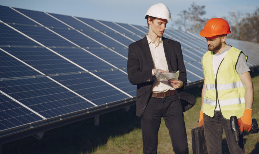 Businessman and worker near solar energy batteries. Business client showing photovoltaic detail to foreman. Two men making deal.